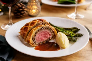 Assiette de bœuf Wellington tranché avec asperges rôties, purée et jus réduit