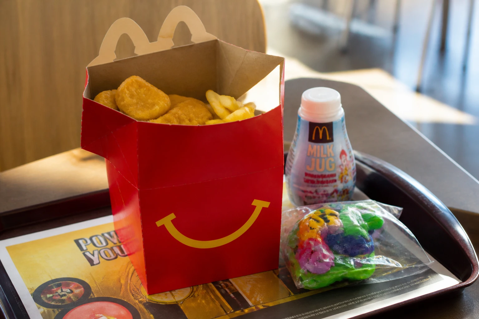 Boîte Happy Meal rouge ouverte avec nuggets, frites, boisson et jouet sur un plateau McDonald's